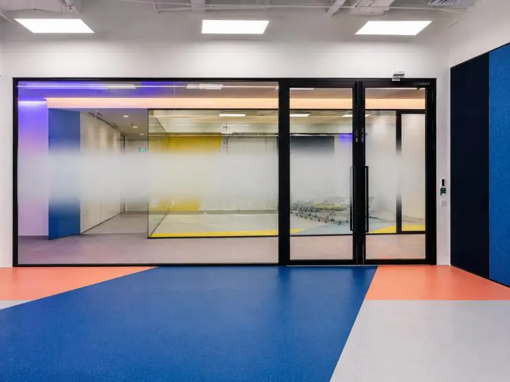 Mapletree: glass partitions with gradient film over blue and orange flooring